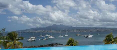 A clear blue pool with a view of boats and mountains in the distance.