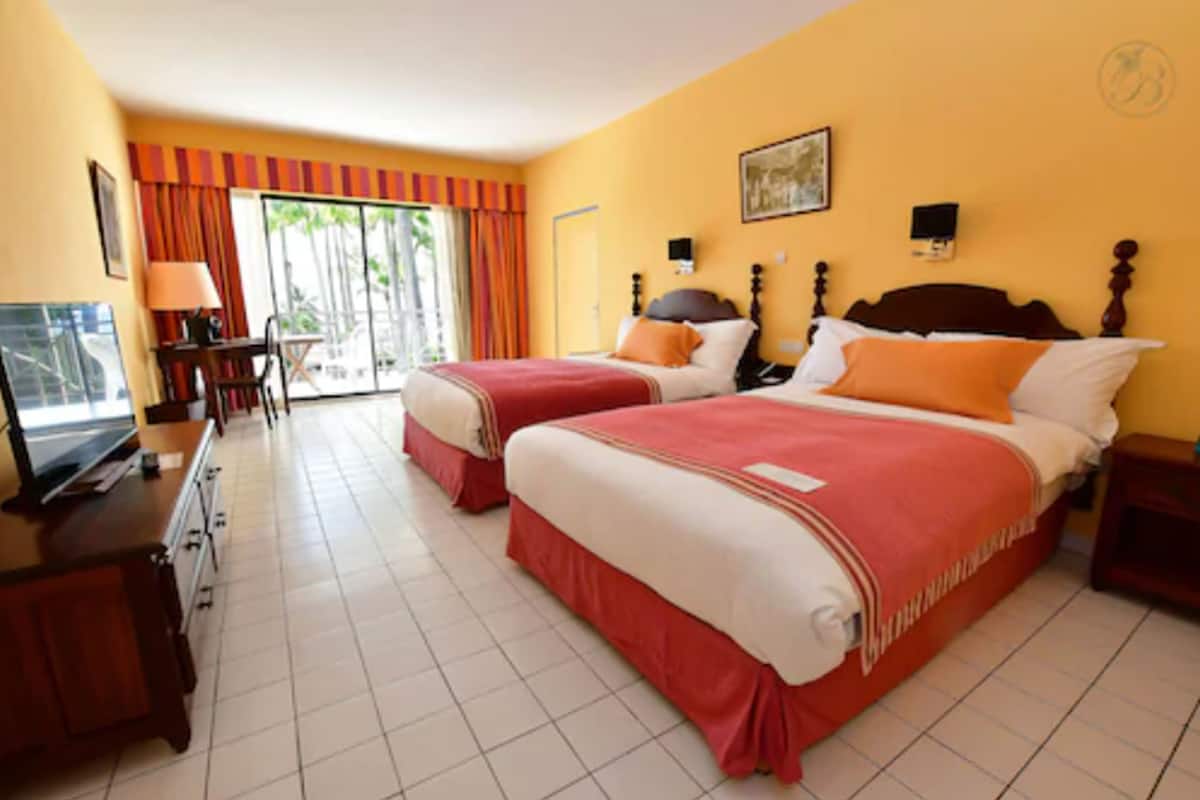 Habitación de hotel con dos camas, un escritorio, un televisor y vistas al exterior.