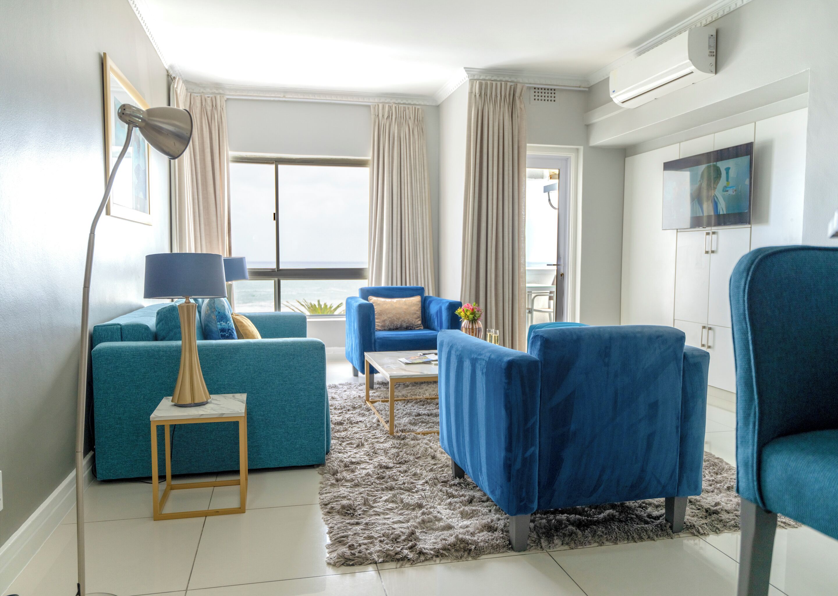 A modern living room with a sofa, armchairs, a coffee table, and a lamp.