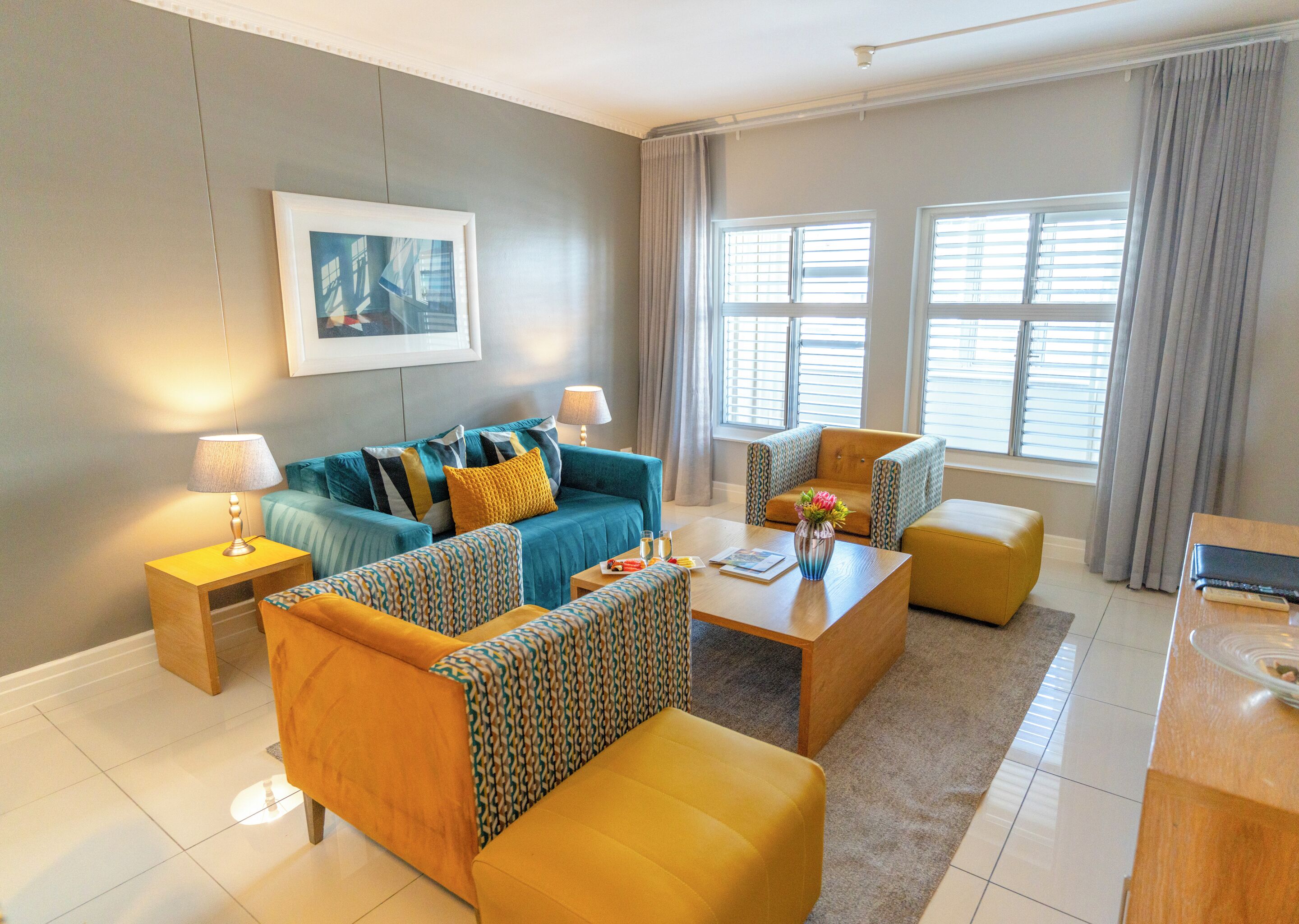 A modern living room with a sofa, armchairs, a coffee table, and a lamp.