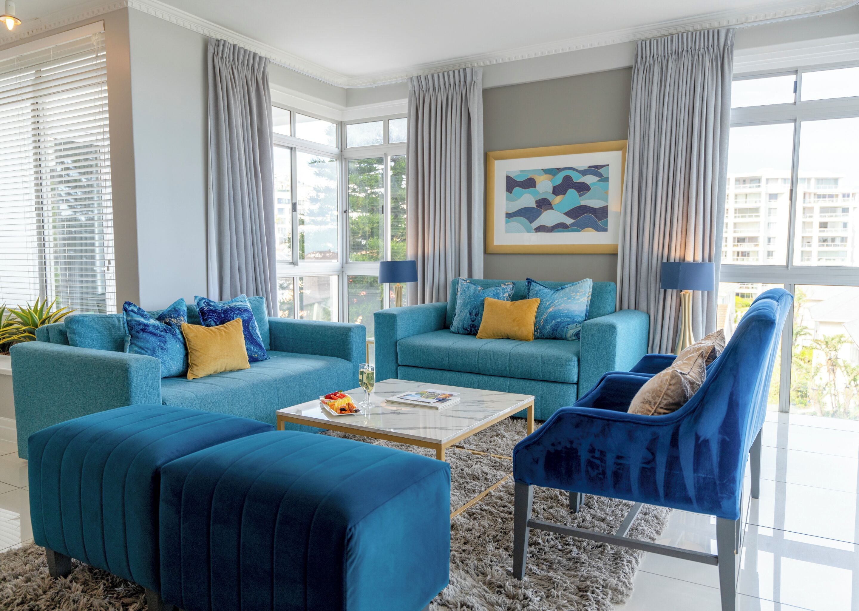 A modern living room with two sofas, a coffee table, and a blue armchair.