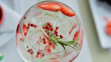 A clear glass with ice cubes, strawberries, and red berries.