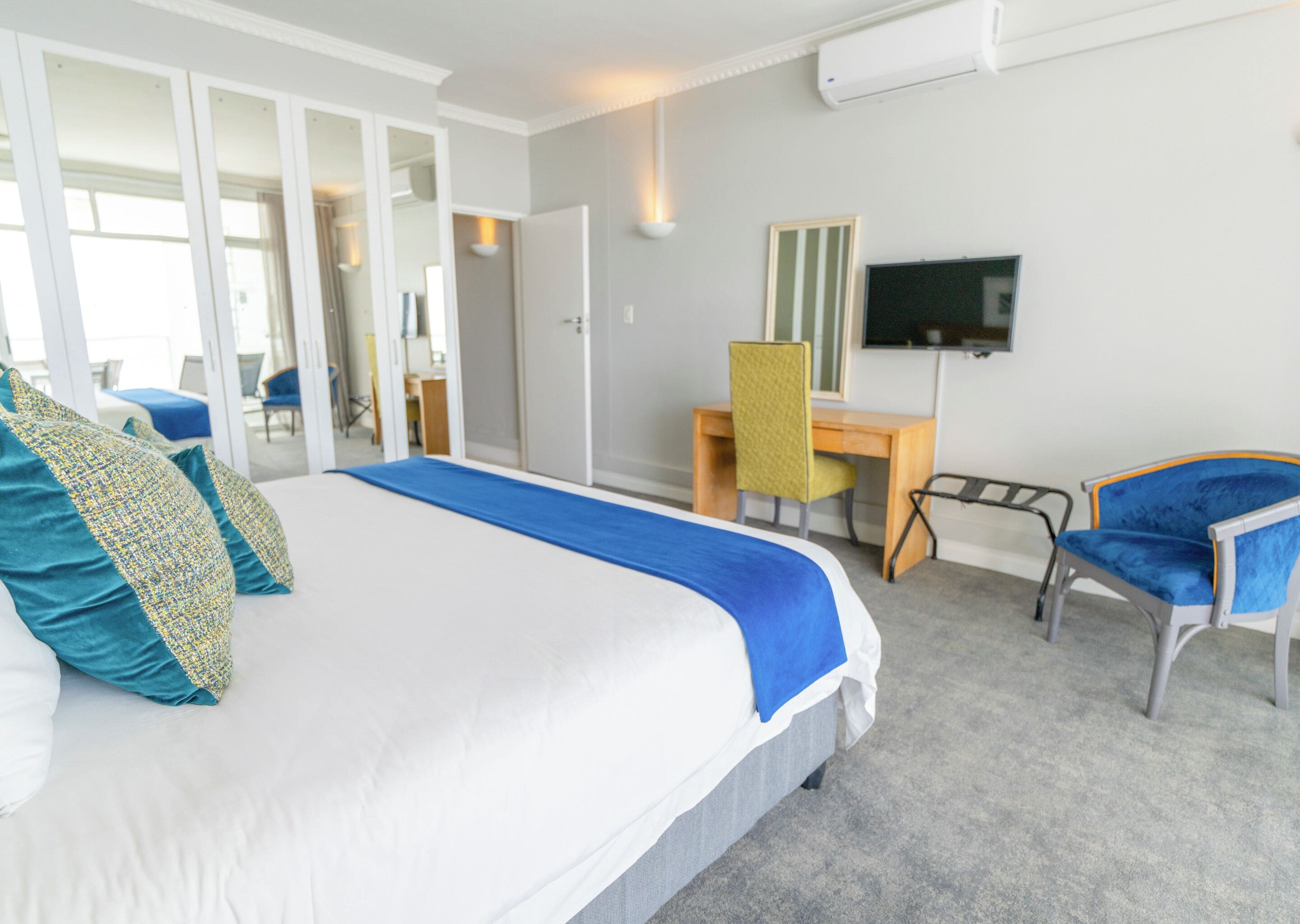 A hotel room with a bed, a desk, a chair, a television, and a wardrobe.