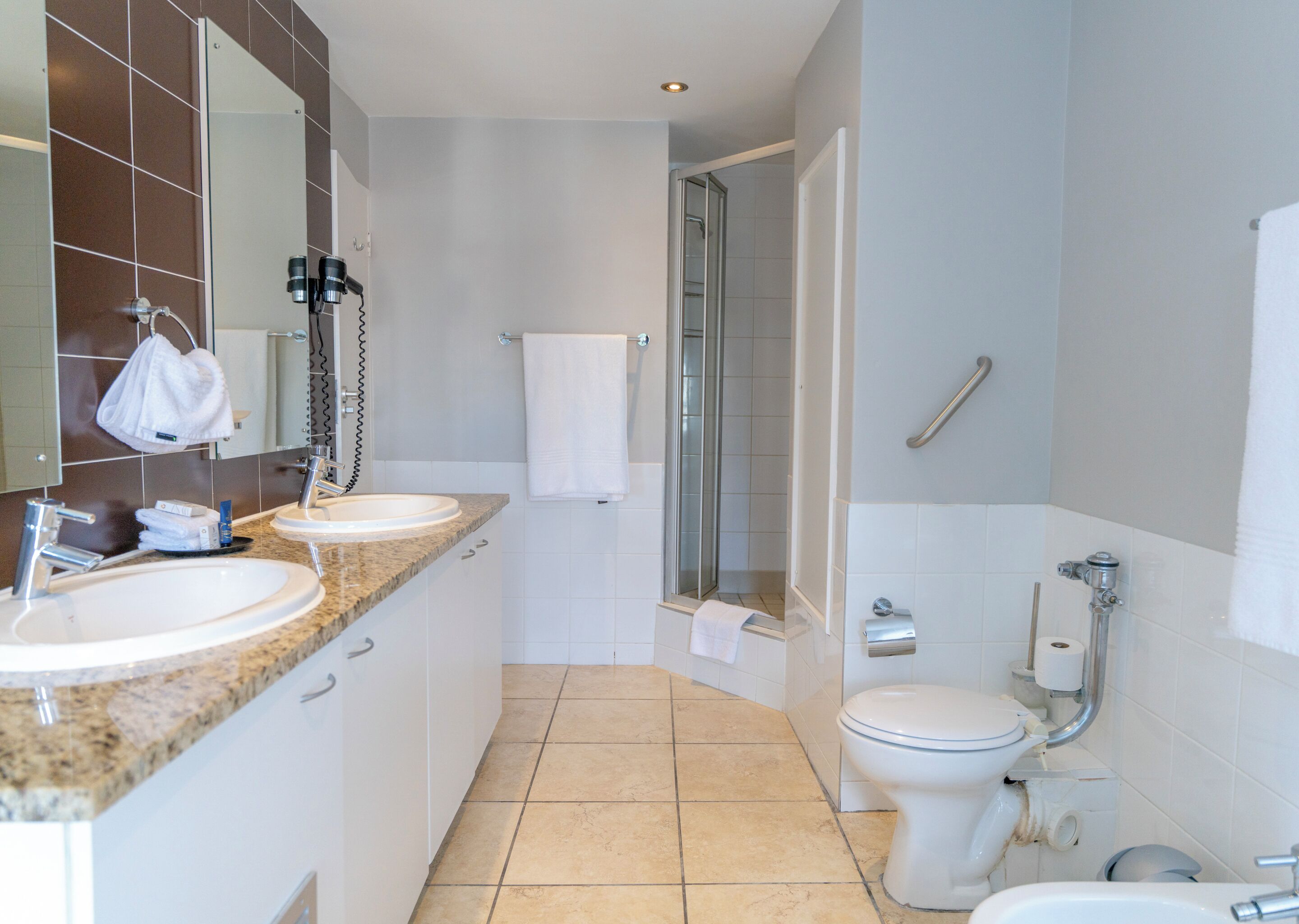 Un baño moderno con dos lavamanos, un inodoro y una ducha.