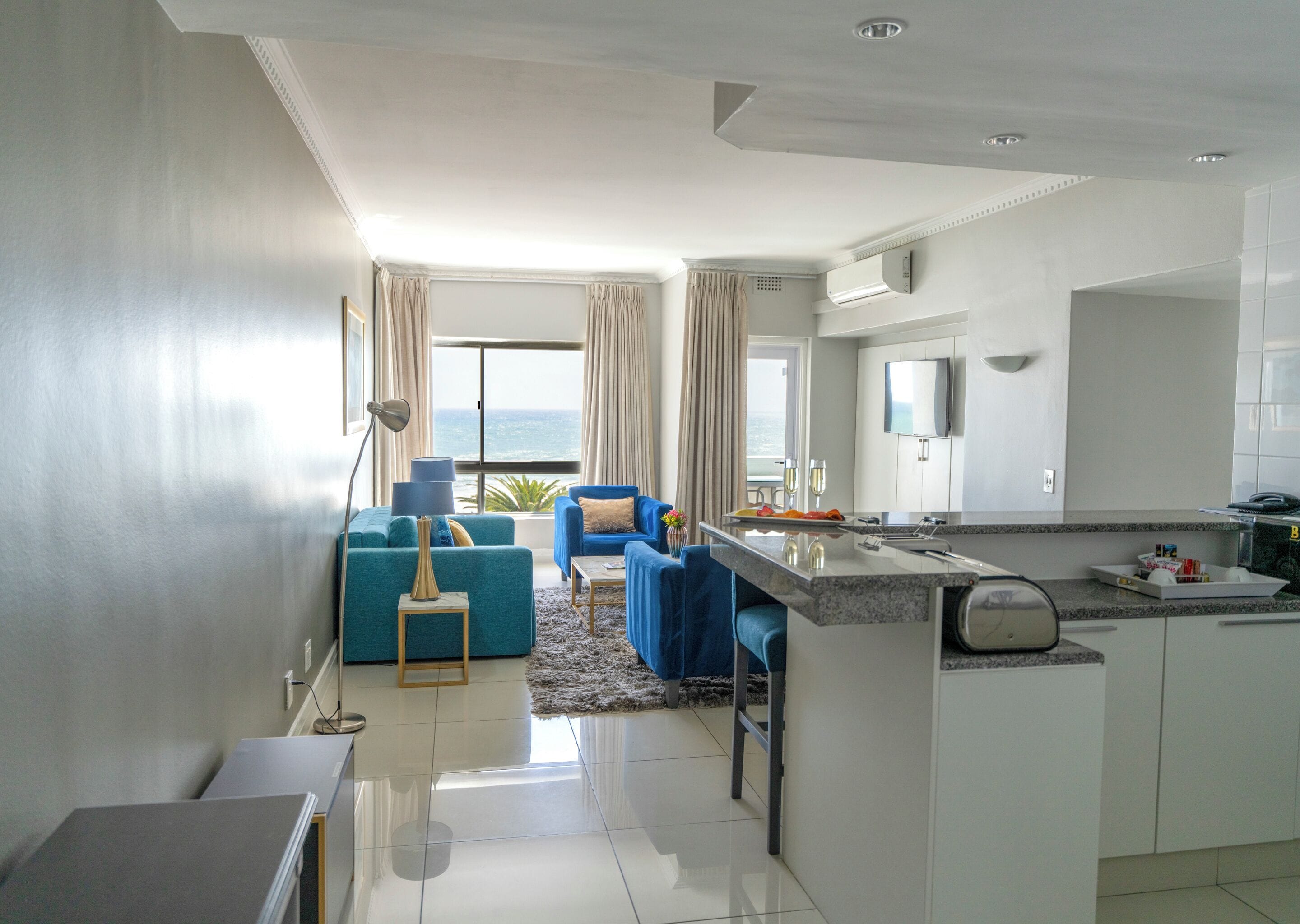A modern living room with a sofa, a coffee table, and a view of the ocean.