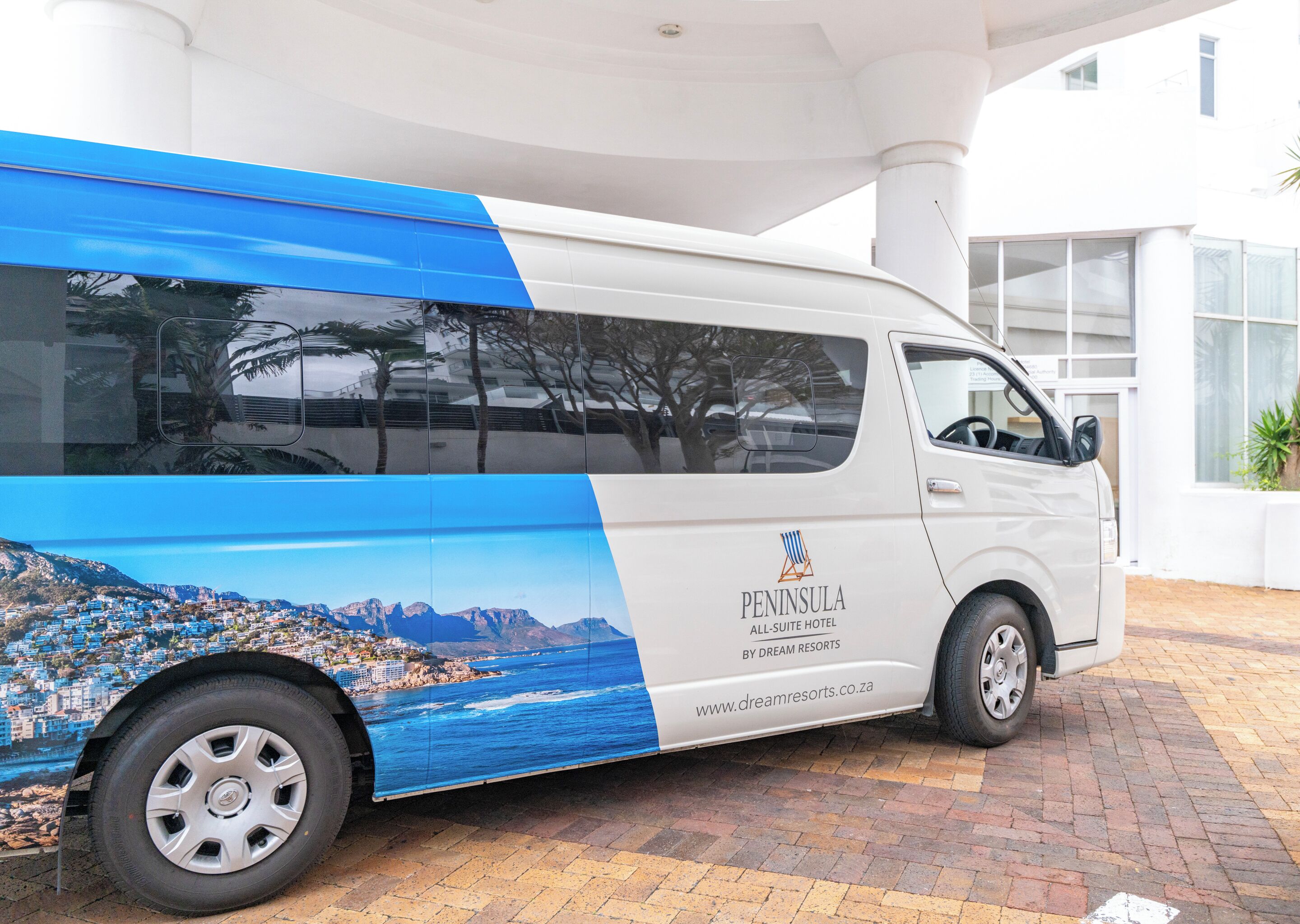 A white van with 'Peninsula All-Suite Hotel' branding and a coastal town image on its side.