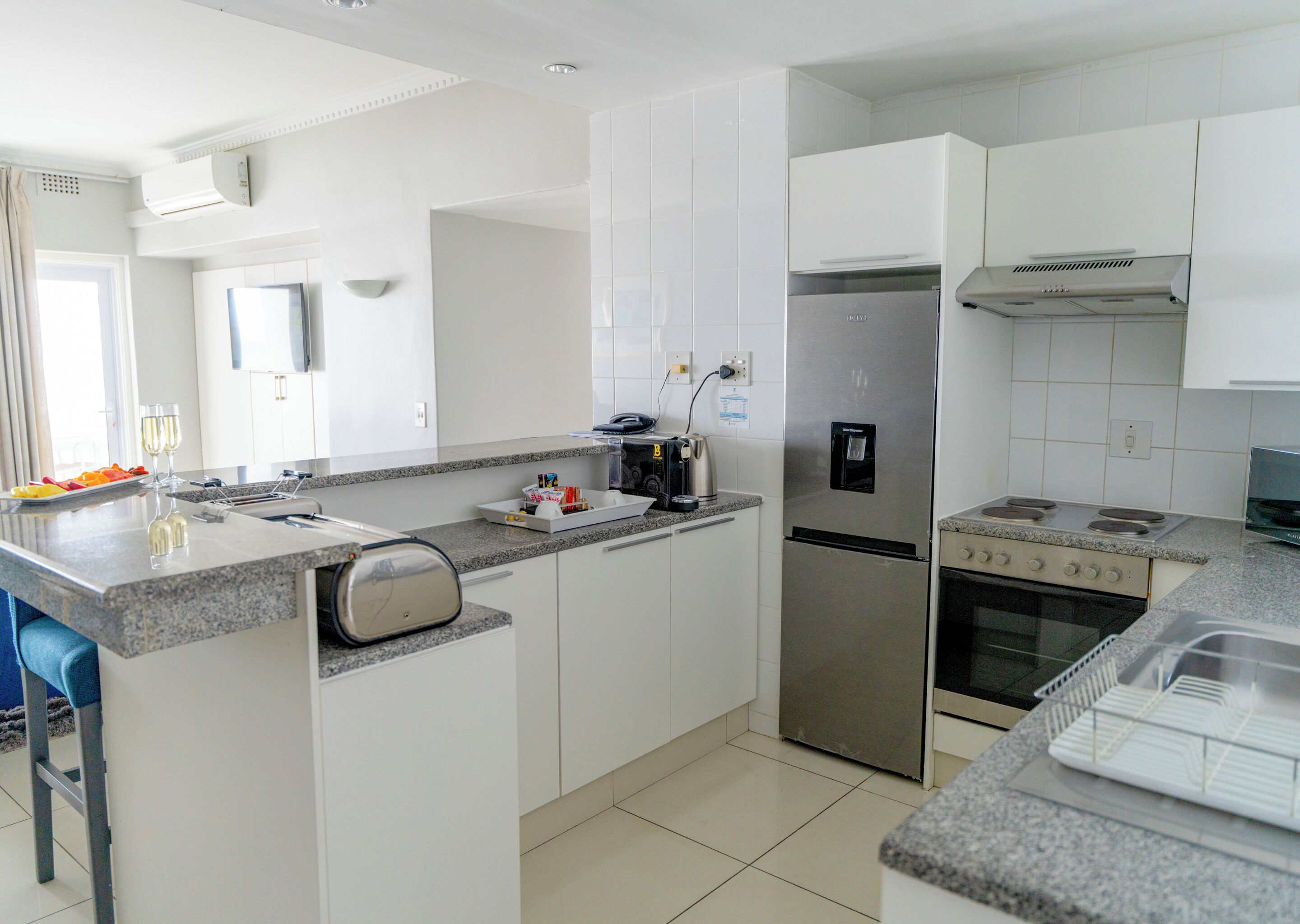 Una cocina moderna con un refrigerador de acero inoxidable, un horno empotrado y una encimera de granito.