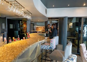 A bar area with a granite countertop, bar stools, and a hanging light fixture. - Peninsula All-Suite Hotel by Dream Resorts (Cape Town)