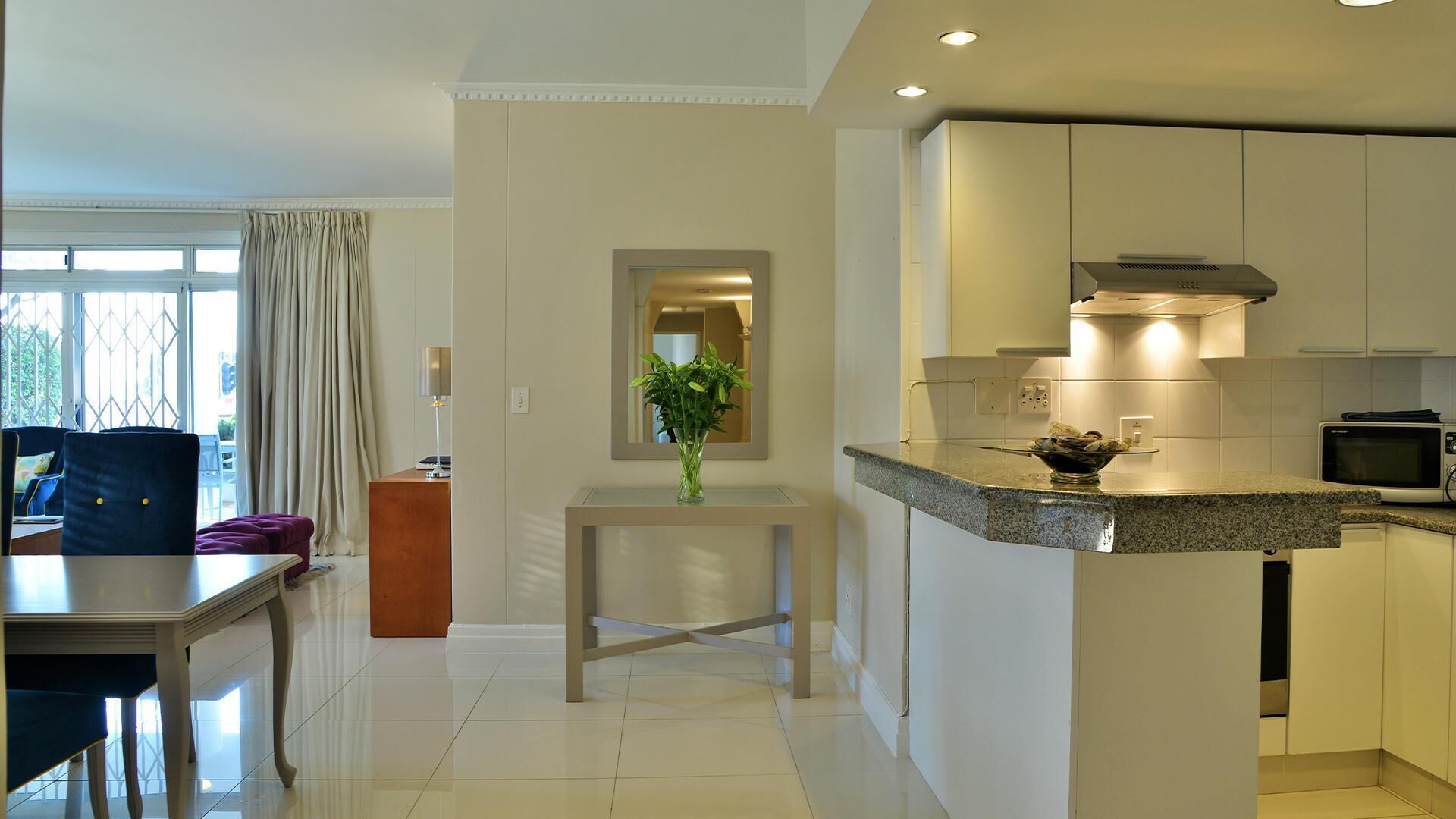 A modern kitchen with white cabinets, a granite countertop, and a microwave.