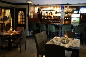 A bar area with multiple seating options, including bar stools and tables, and a variety of bottles and glasses on shelves. - Harmony Marina Suites (Gros Islet)