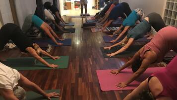 Eine Gruppe von Menschen nimmt an einer Yoga-Klasse teil und sitzt auf Yogamatten in einem Raum mit Holzböden.