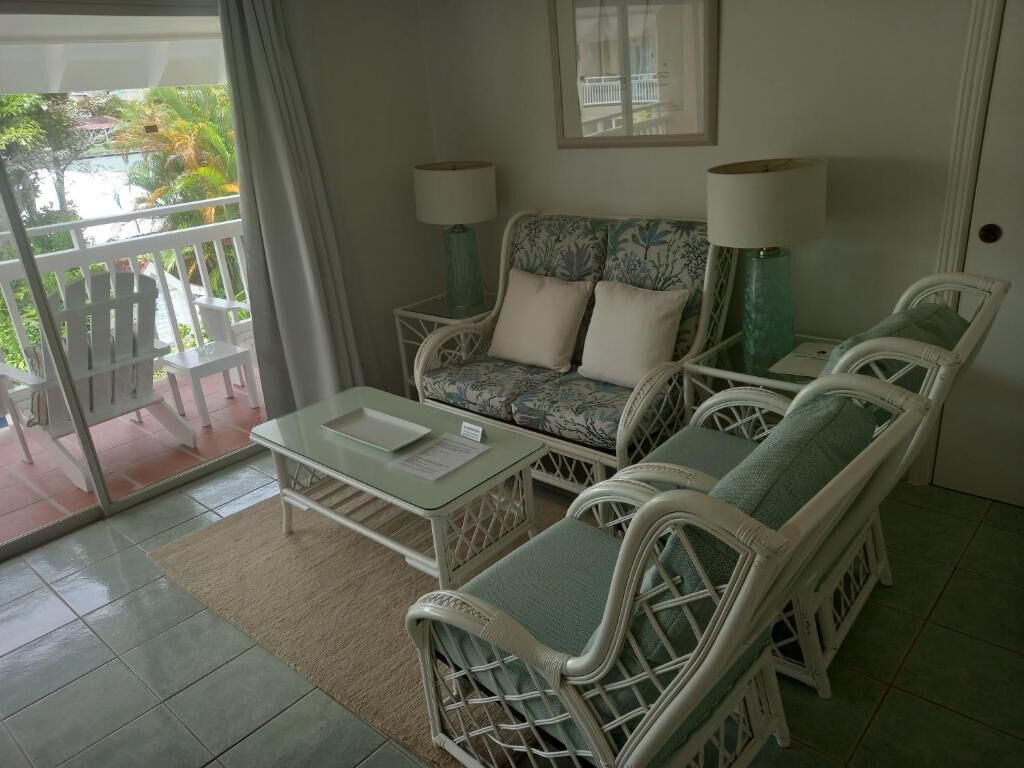 A room with a balcony, a sofa set, two lamps, and a small table.