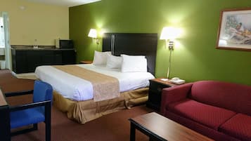 Habitación de hotel con cama, escritorio, silla, sofá, televisor y un cuadro en la pared.