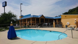 Hotel com piscina, área de estar externa e estacionamento cercado.