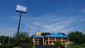 Um Travelodge Inn & Suites com teto azul e uma torre central, rodeado por vegetação e céu claro.