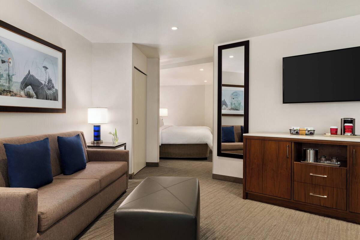 Quarto de hotel com sofá, cama, armário de madeira e TV de tela plana.