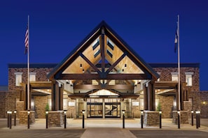 A modern building with a prominent triangular roof structure, large glass entrance, and stone facade.