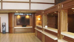 A reception area with a sign for the meeting room and restrooms, a water dispenser, and a counter with a lamp. - Trade Winds Central Inn (Tulsa)