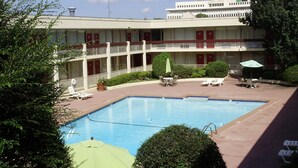 A hotel with a swimming pool, outdoor seating, and a building with multiple balconies. - Trade Winds Central Inn (Tulsa)