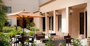 Relax in a serene outdoor space with comfortable seating, a dining table, and lush greenery.