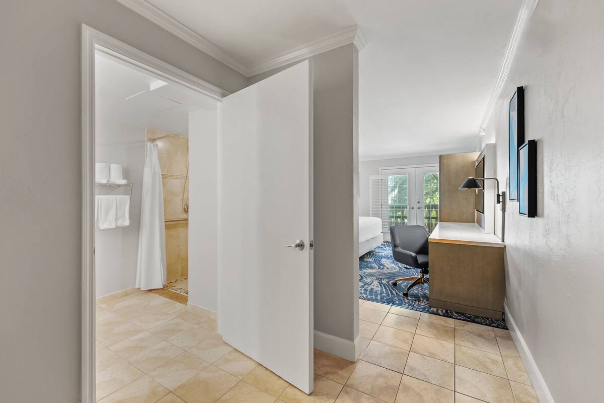 Une chambre d’hôtel avec salle de bain, un bureau et une vue sur l’extérieur.