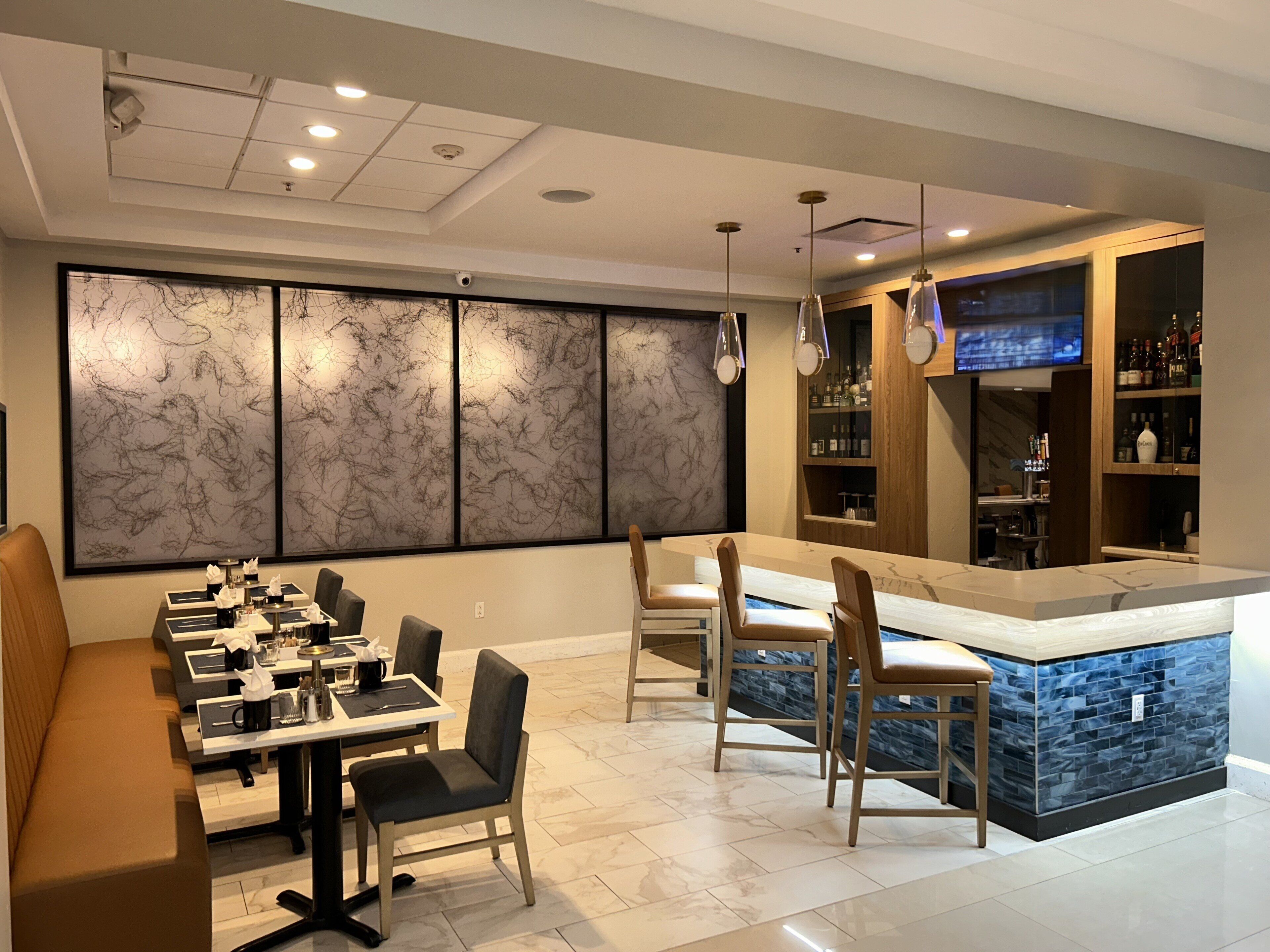 A modern kitchen with a dining area, marble backsplash, and a bar with a stone countertop.
