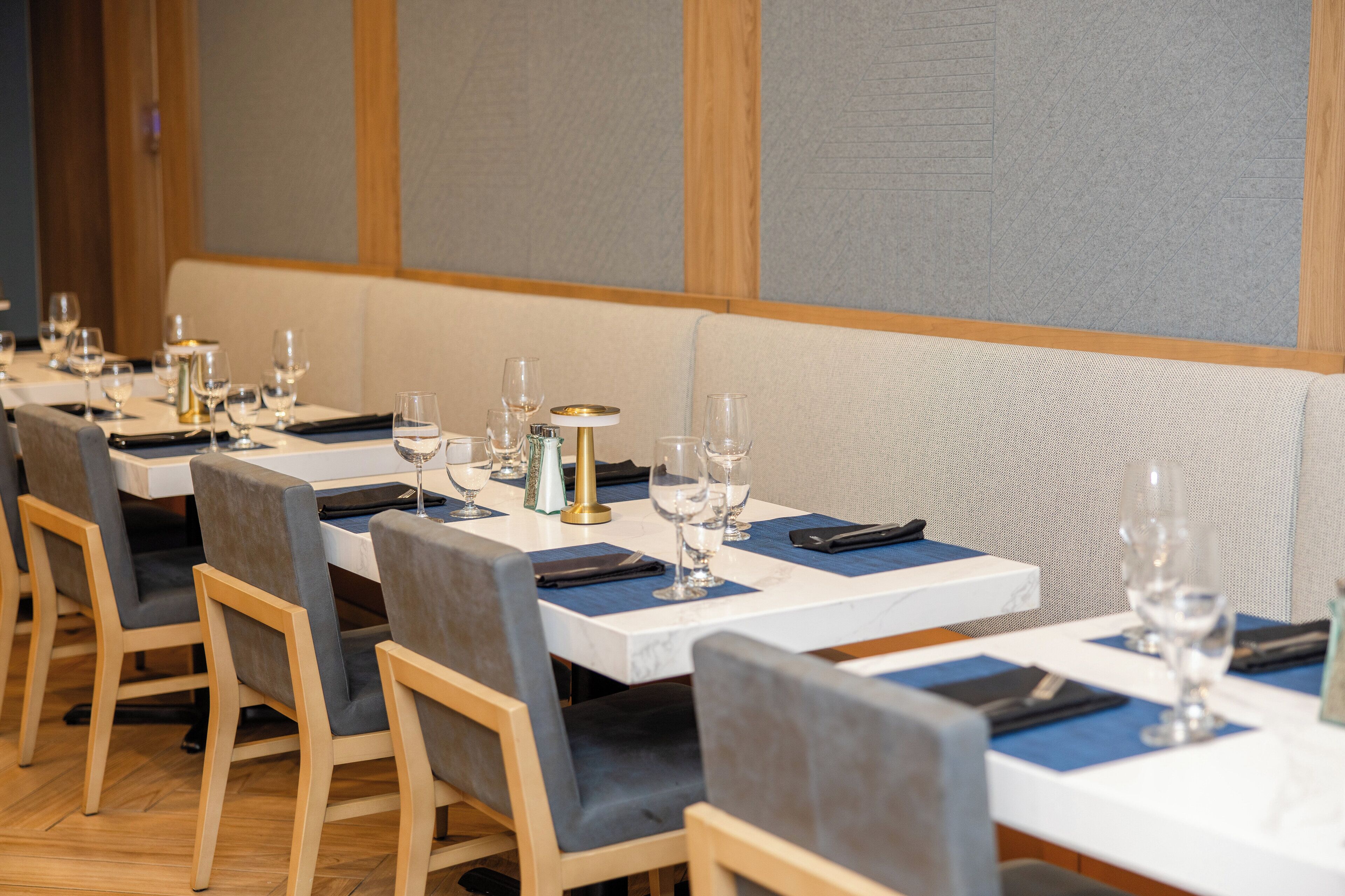 A restaurant with multiple tables, each set with chairs, glasses, and a small table centerpiece.