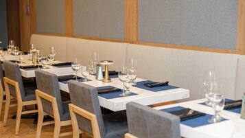 A restaurant with multiple tables, each set with chairs, glasses, and a small table centerpiece.