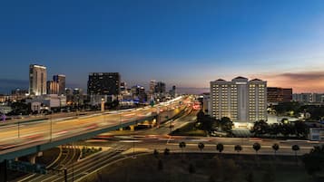 Un paisaje urbano con un hotel destacado, varios edificios altos y una autopista concurrida con estelas de luz.