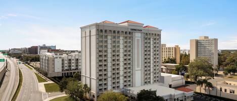 A high-rise hotel with a classic architectural design, featuring multiple balconies and a central courtyard.