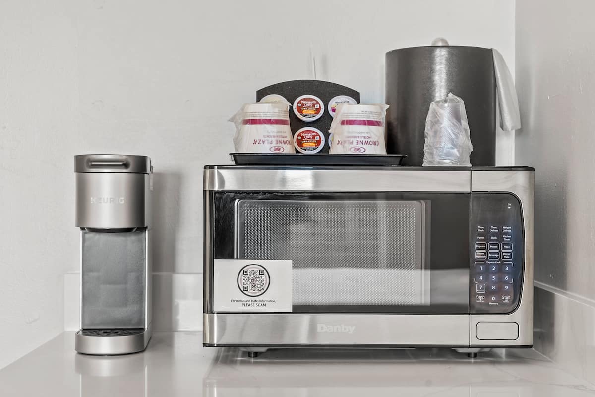 Une cuisine moderne équipée d’une machine à café, d’un four à micro-ondes et d’un distributeur d’eau.