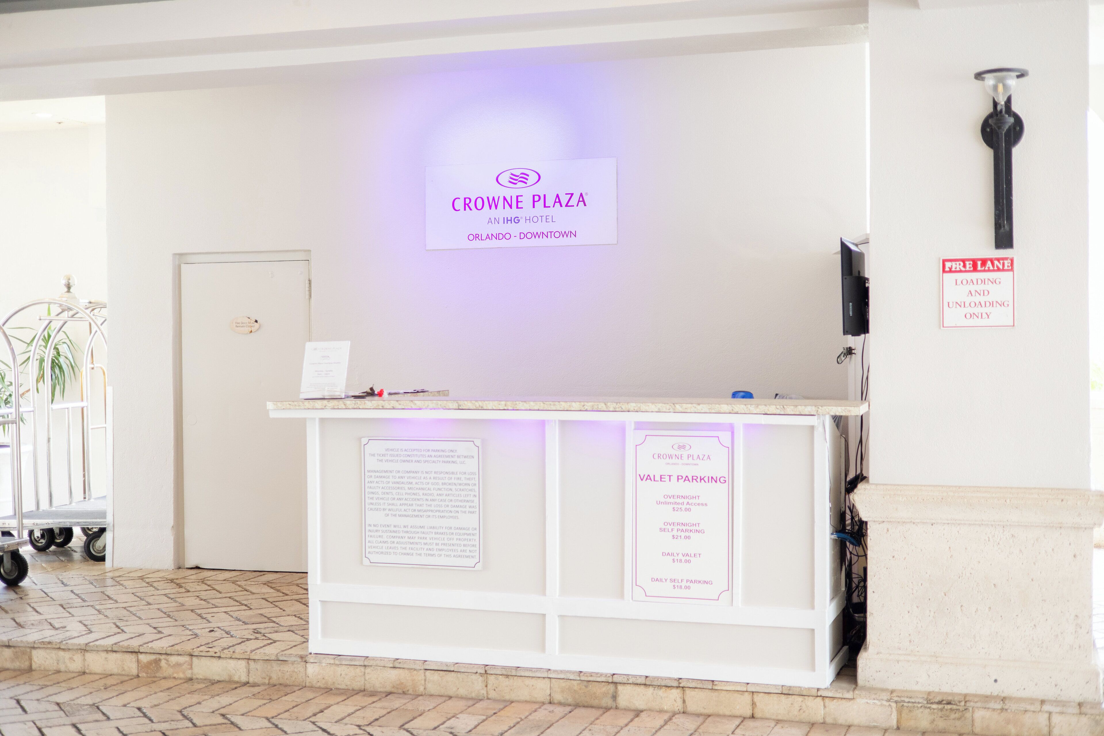 Un comptoir d’accueil dans l’hôtel Crowne Plaza, avec un panneau indiquant les tarifs du service de voiturier.