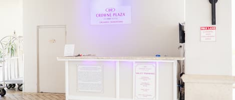 A reception desk at Crowne Plaza with a sign indicating valet parking rates.