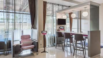 A modern hotel room with a seating area, a television, and a digital menu board.