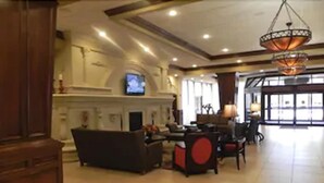 A spacious lobby with a fireplace, seating area, and a television mounted on the wall. - Decatur Conference Center & Hotel (Decatur)
