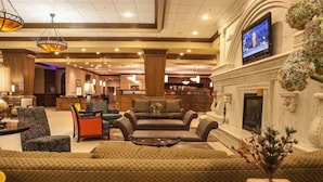 A hotel lobby with a seating area, a fireplace, and a television mounted on the wall. - Decatur Conference Center & Hotel (Decatur)