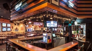 A bar area with multiple seating options, a Red Bull refrigerator, and a television screen. - Decatur Conference Center & Hotel (Decatur)