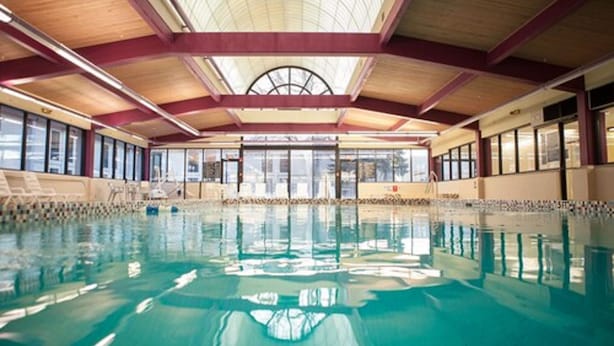 An indoor swimming pool with clear glass walls, wooden beams, and a high ceiling. - Decatur Conference Center & Hotel (Decatur)