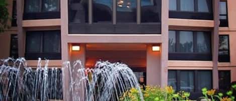Un hotel de varios pisos con un patio central que cuenta con una fuente y una piscina.