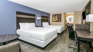 Une chambre d’hôtel avec deux lits, un bureau, une chaise et une télévision.