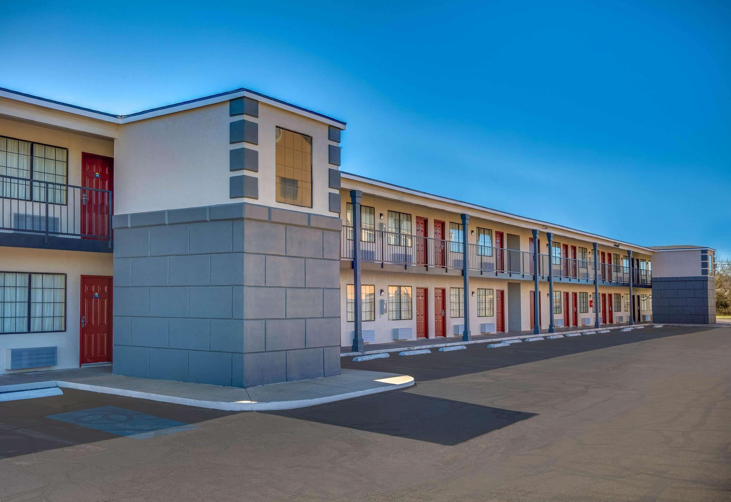 A multi-story motel with a central corridor, individual rooms on either side, and a parking lot in front.