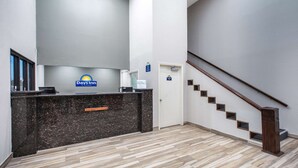 Un espace d’accueil avec une enseigne Days Inn, un comptoir de réception, un escalier et une porte.