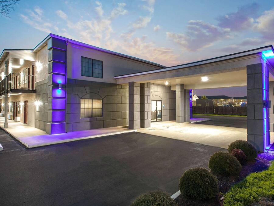 Un hotel moderno con una entrada espaciosa, una zona de estacionamiento techada y una fachada bien iluminada.