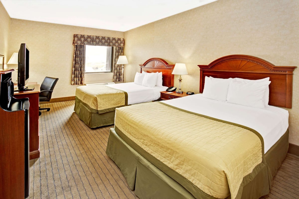 Une chambre d’hôtel avec deux lits, un bureau avec un ordinateur et une télévision.