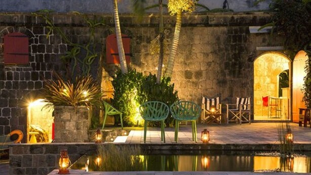A courtyard with a pool, stone walls, and outdoor seating.