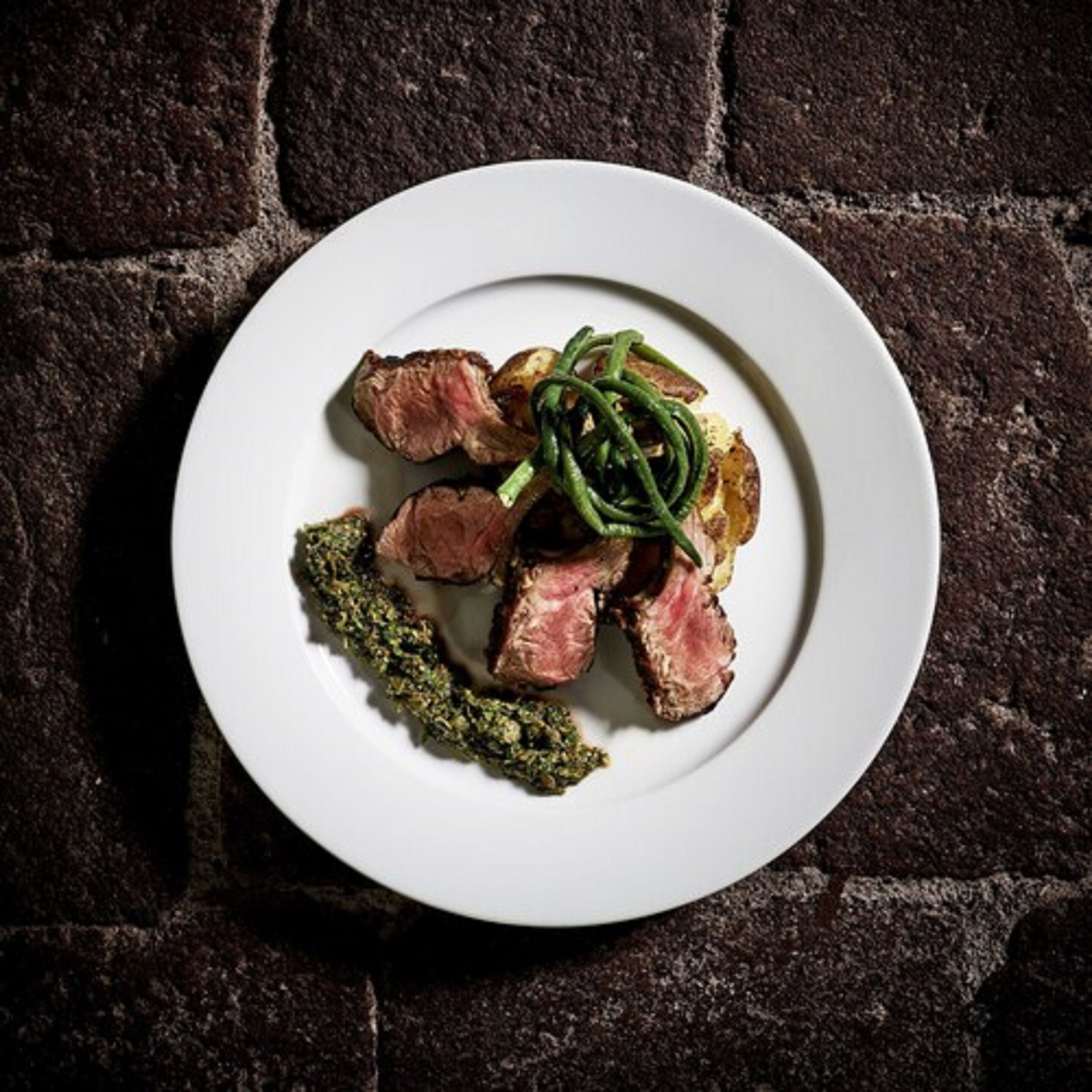 Ein Teller mit einem Steak und grünen Bohnen.
