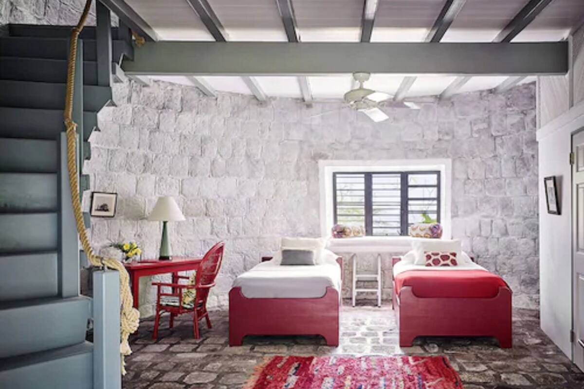 A cozy room with a stone wall, a bed, a desk, and a chair.