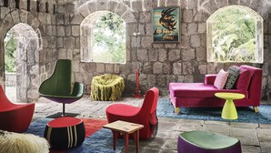 A room with stone walls, arched windows, and a mix of modern and classic furniture.