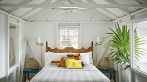A bedroom with a wooden bed, white walls, a window, and a ceiling fan.