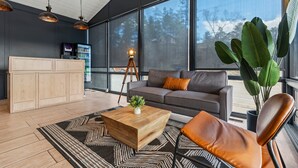 A modern living room with a large window, a sofa, a coffee table, and a cabinet.